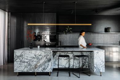 A monochromatic backdrop in the kitchen enlivens the dramatic granite island bench.