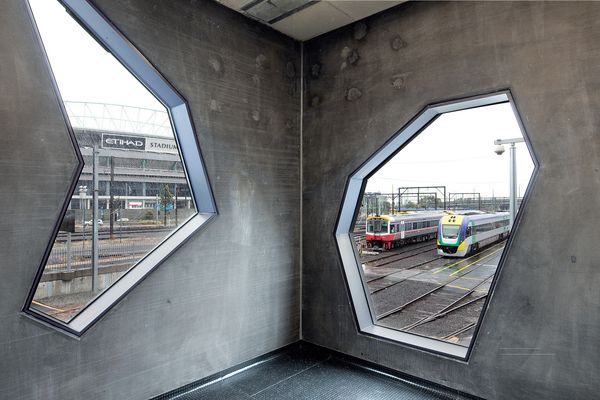 Irregularly shaped windows frame views of Melbourne's rail yards and city skyline.
