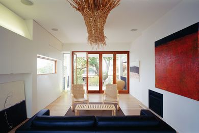 The living room on the third floor enjoys views of Sydney Harbour through the treetops. Artwork: Hannah Hall.