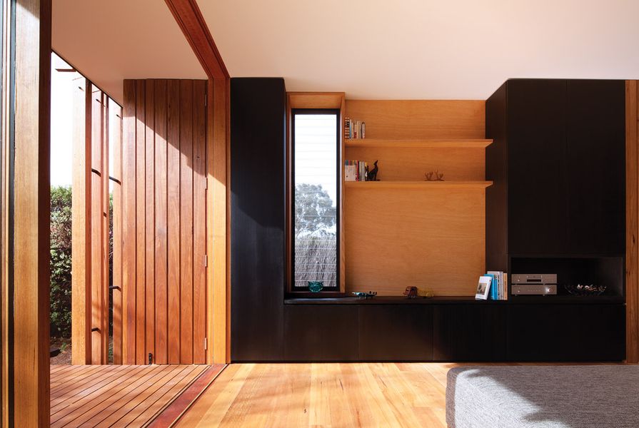 The new living space connects to a timber deck and garden through full-height glazing and a large sliding door.