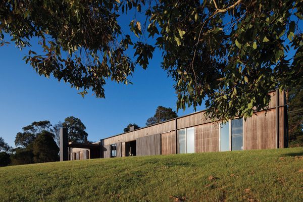The rectilinear home, clad in spotted gum boards, hugs the contours of the site.