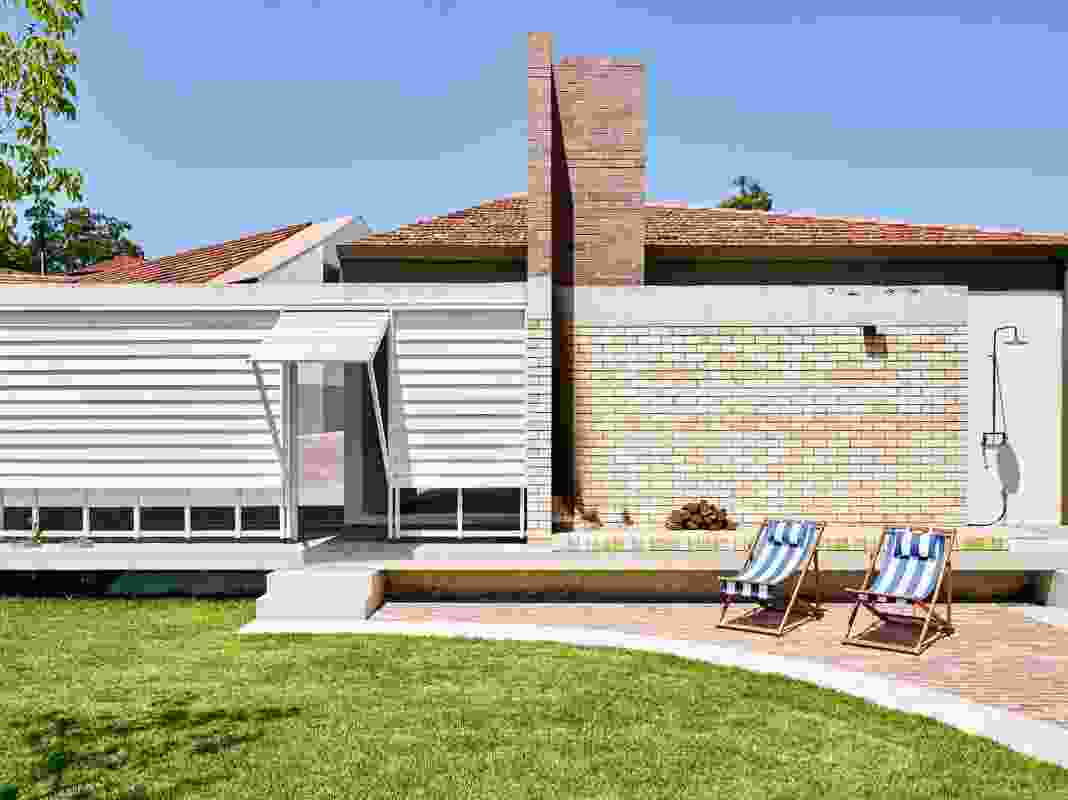 An open-air brick fireplace at the end of the garden sits adjacent to a swimming pool.