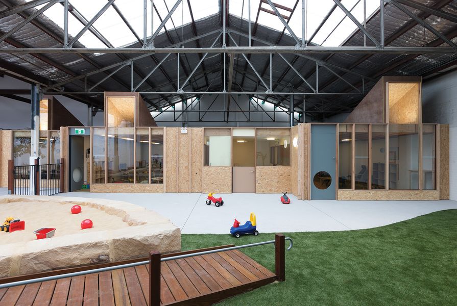 An indoor landscape unfolds beneath the pitched roofs and steel trusses of the warehouse.