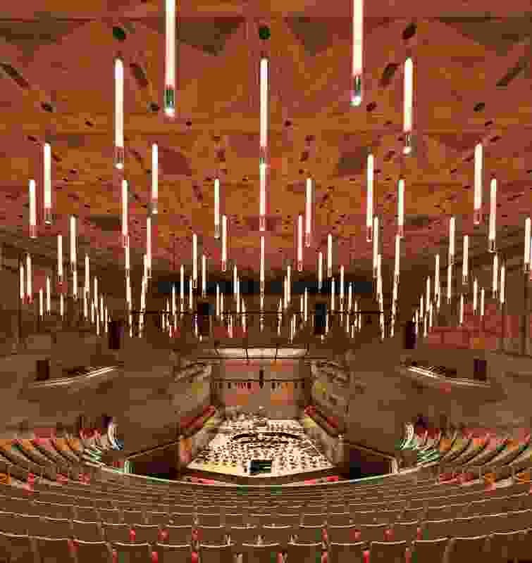 The auditorium’s suspended tube lighting, like a sea of glowing batons, sustains the shining lights and embodied movement of the Hall’s annular foyers.