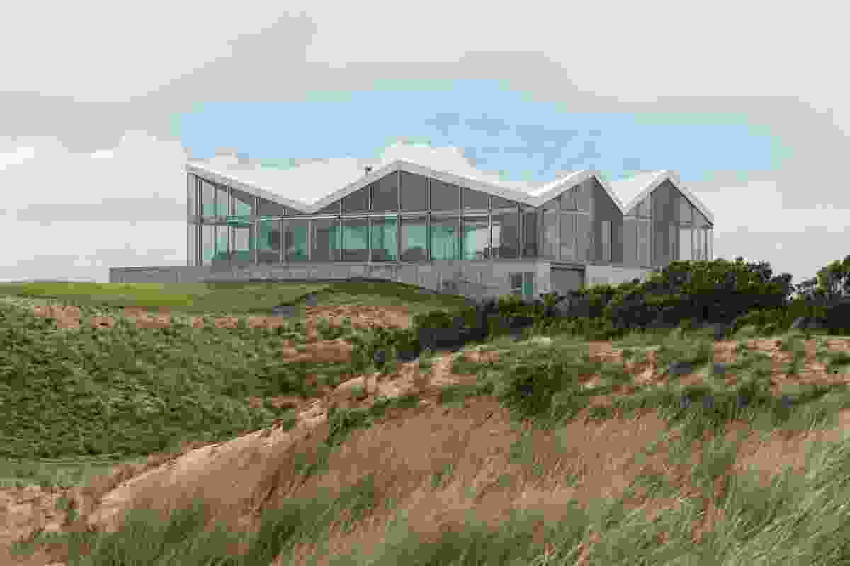 The house’s concrete base rises above the dunes, as if it were a raft breasting waves.