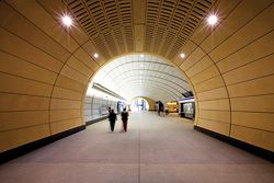 View down the long tunnel of the unpaid concourse at Macquarie University Station.