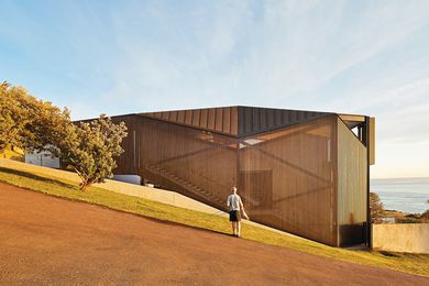 Three flights of finely detailed concrete stairs are visible through the dark, faceted form of the home.