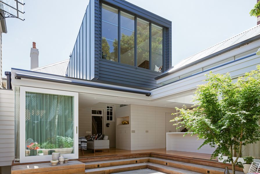 The rear of the home opens out to a planted courtyard, with the box-like addition casting a watchful eye overhead.