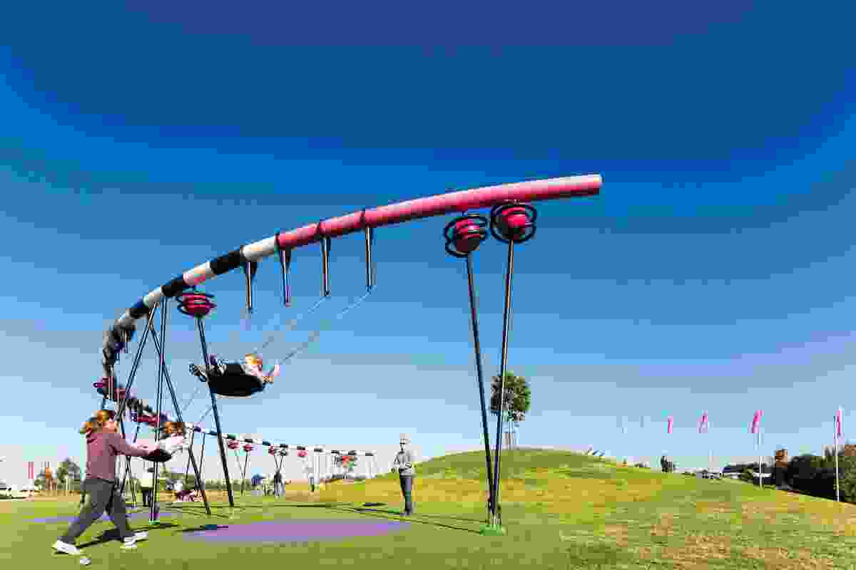 A semicircular swing set parallels the nearby grass mound.