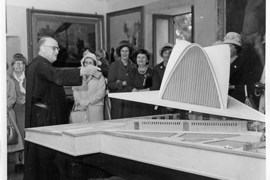 Fr Mauro Enjuanes showing the model of the cathedral to a group of local residents, c. 1959. Accession number 74893P.