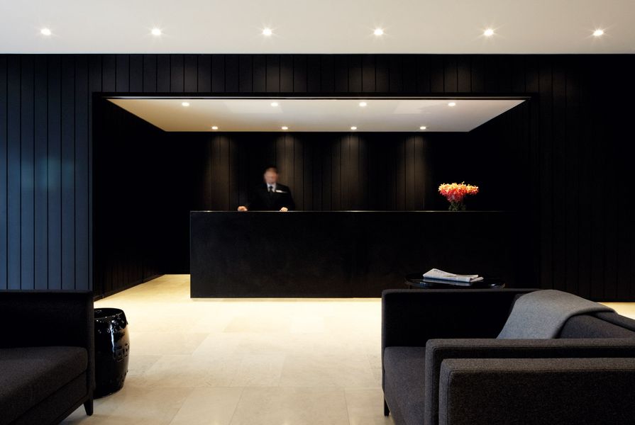 Black wall panels contrast with white limestone flooring in reception.