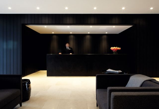 Black wall panels contrast with white limestone flooring in reception.