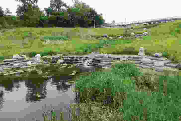 A stream rushes over recycled concrete slabs into the lake at Henry Palmisano Park.