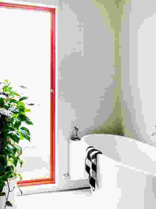 The bold tangerine orange from the doors in the living room is brought through and appears in the bathroom on a powder-coated window frame. 