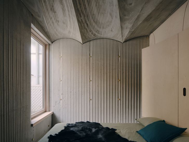 The east bedroom features a concrete vaulted ceiling and textured concrete walls.