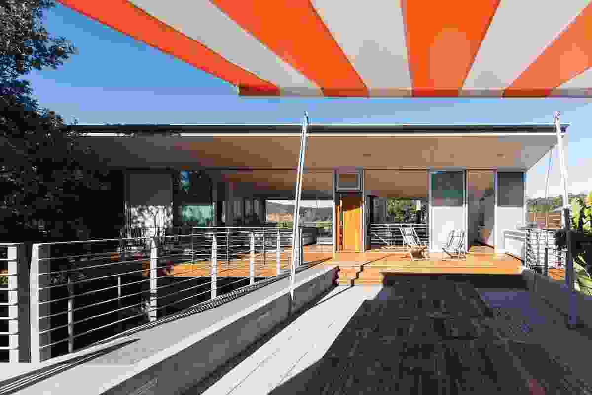 The northern deck features a sunken lounge with a large retractable awning in a wide bright stripe, recalling beach umbrella patterns.