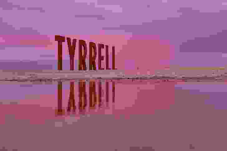 Near the edge of the lake, large corten steel structures spell “TYRRELL” in letters far taller than a human.