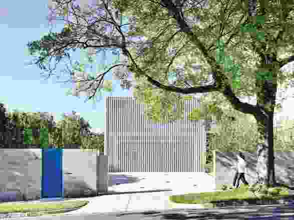 A white metal grille and dramatic blue gate conceal what’s inside and define the exterior of the dwelling.

