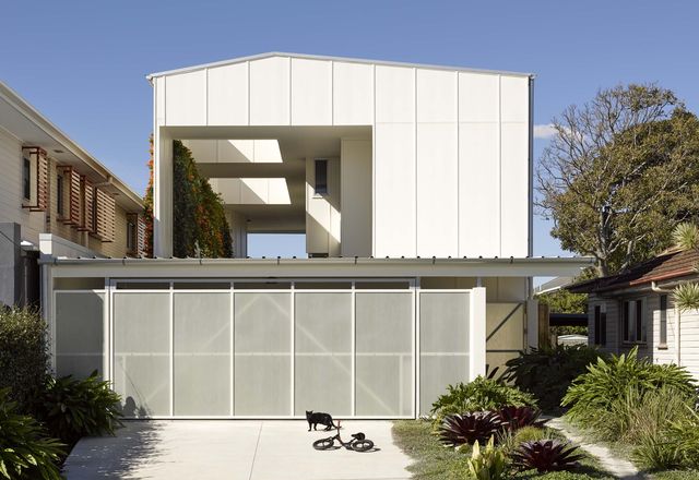 From the street, a gable roof and fence-like perforated garage panels suit the suburban locale.