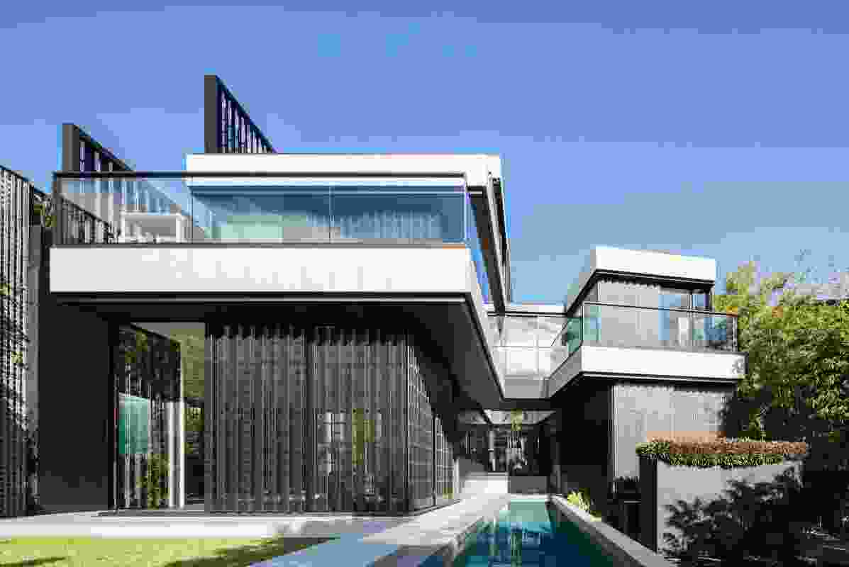 At the rear, the house splits into two wings, bounded by a bridge that joins the front edges of the two parts over a lap pool.