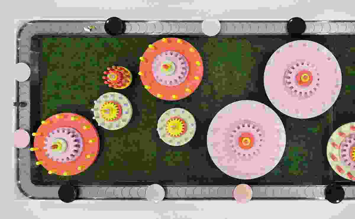 The conveyor belt is "themed" with colourful spinning cogs on a faux grass field.