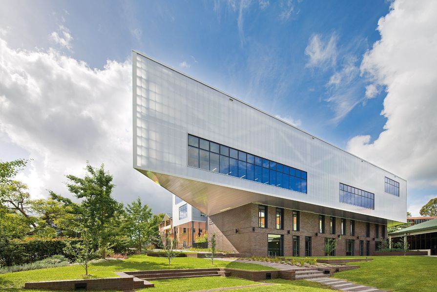 The two-storey polycarbonate-clad volume containing a learning centre cantilevers over a manganese brick base.