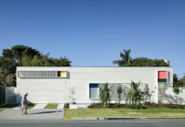The entry facade is a playful composition of blocks of colour and battened screens on a white background.